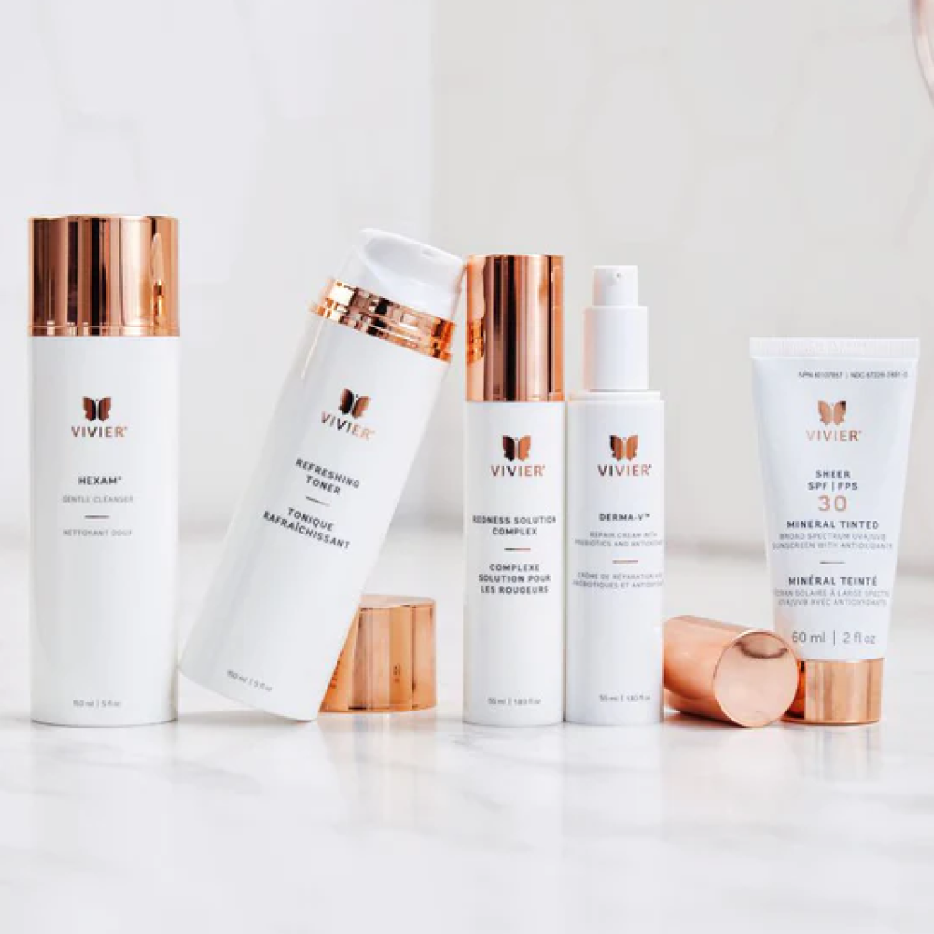 Assorted pack types of Vivier Sensitive Skin Program, featuring pump bottles, squeeze tubes, and sleek packaging, elegantly arranged with a Vivier-branded vegan leather bag