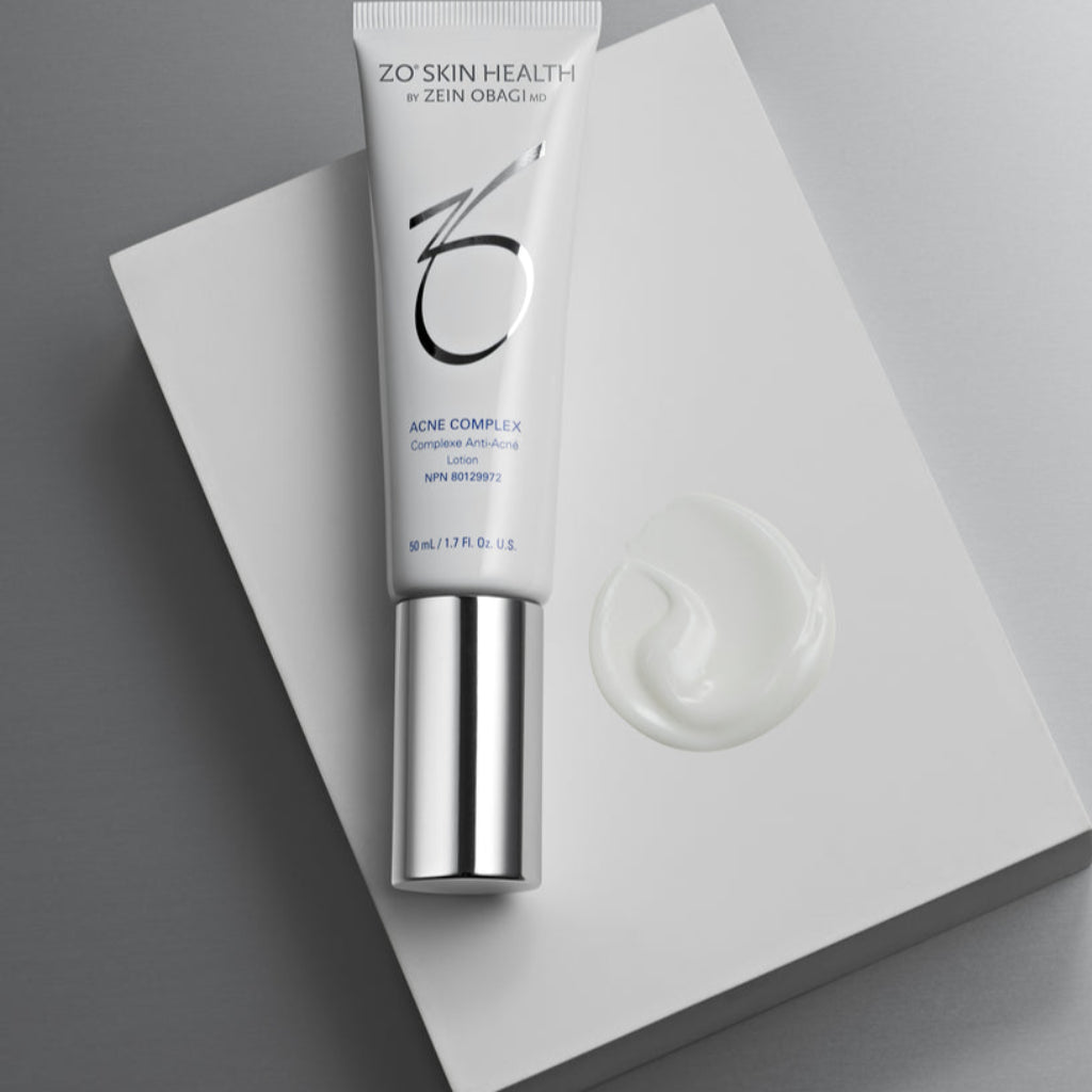 Product image of ZO® Acne Complex placed on top of a white box, with a visible swatch of the lightweight treatment beside it, highlighting its smooth texture and advanced formula designed to treat breakouts, prevent future acne, and improve post-acne marks and skin texture