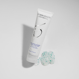 ZO Skin Health Exfoliating Cleanser 60ml travel size – white tube with water droplets shown next to a textured swatch of the gel cleanser containing green exfoliating beads, designed for normal to oily skin