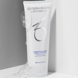 ZO Skin Health Hydrating Cleanser tube with silver and blue branding, surrounded by bubbles, against a sleek white and gray background