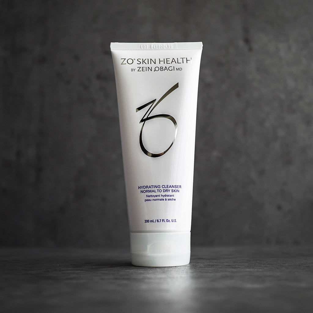 ZO Skin Health Hydrating Cleanser tube with silver and blue branding, standing upright against a dark gray textured background