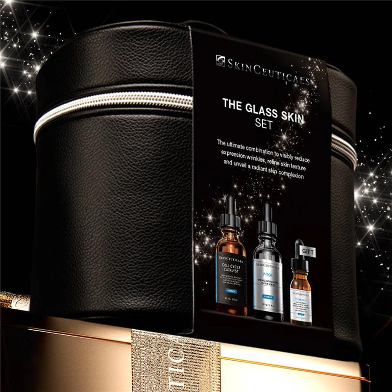The Skinceuticals Holiday The Glass Skin Set displayed on top of a gold box with gold ribbon against a starry night background