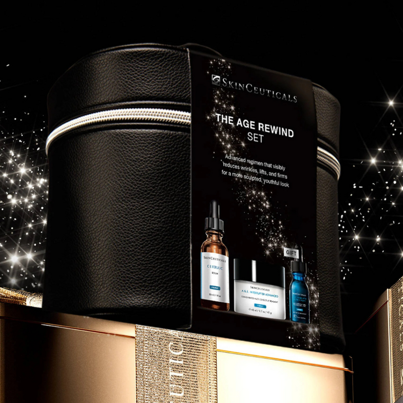 The Skinceuticals Holiday The Age Rewind Set displayed on top of a gold box with gold ribbon against a starry night background