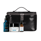 A skincare gift set featuring a black faux-leather zippered case with a top handle, alongside three skincare products: a blue dropper bottle of Brévibrations A.S.