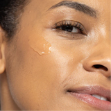 Close-up image of a person's cheek with a dab of Vivier HEXAM Gentle Gel Cleanser. The cleanser appears as a translucent gel on the skin, subtly reflecting light. The person's skin is visible around the gel, emphasizing the application process. The background is soft-focused to highlight the action on the face.