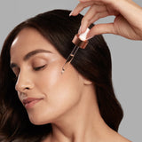 Fair skinned woman putting on the Vivier Serum 30 using its glass dropper