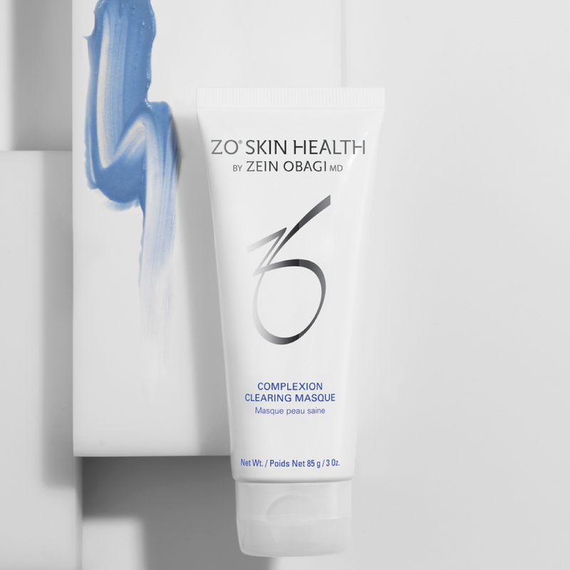 Product image of ZO® Complexion Clearing Masque placed in front of a white box, with a visible swatch of the clay masque highlighting its smooth, creamy texture—designed to absorb excess oil, clear pores, and reduce breakouts while hydrating the skin