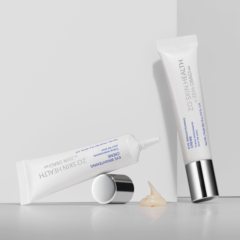 ZO Eye Brightening Crème in a sleek tube, with a small amount of cream dispensed in front of a white product box, highlighting its smooth texture and packaging