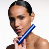Medium tone woman holding the blue bottle of the new ZO Skin Helath Peptide Facial Refining Concentrate against a white background