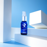 A bottle of iS Clinical Poly Vitamin Serum placed on a white pedestal with a blue background.