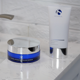 iS Clinical Hydra-Intensive Cooling Masque and the Warming Honey Cleanser on a bathroom counter with a tiled wall background