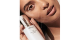 A radiant woman with glowing skin holding a SkinMedica serum bottle, showcasing professional-grade skincare