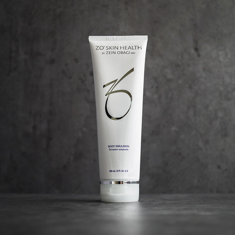 ZO Body Emulsion bottle placed on a grey concrete background, designed to hydrate and smooth dry, rough skin