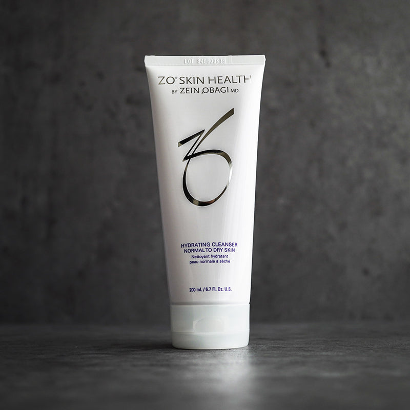 ZO Skin Health Hydrating Cleanser tube with silver and blue branding, standing upright against a dark gray textured background